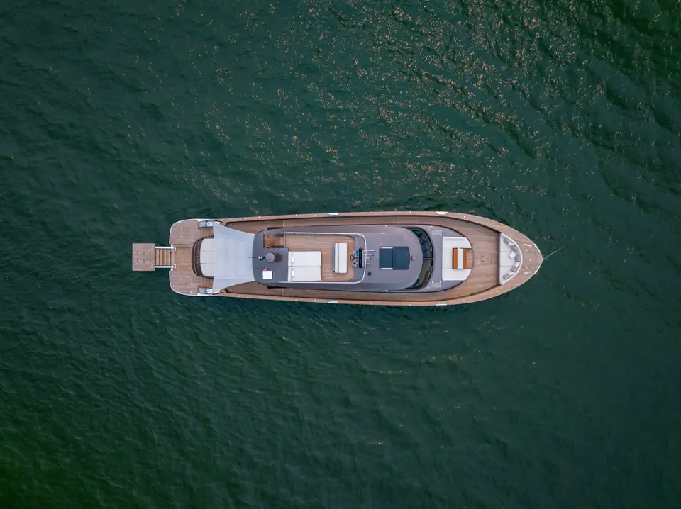 The flybridge from directly above: helm forward, seating and sunbed aft, tender garage shut.